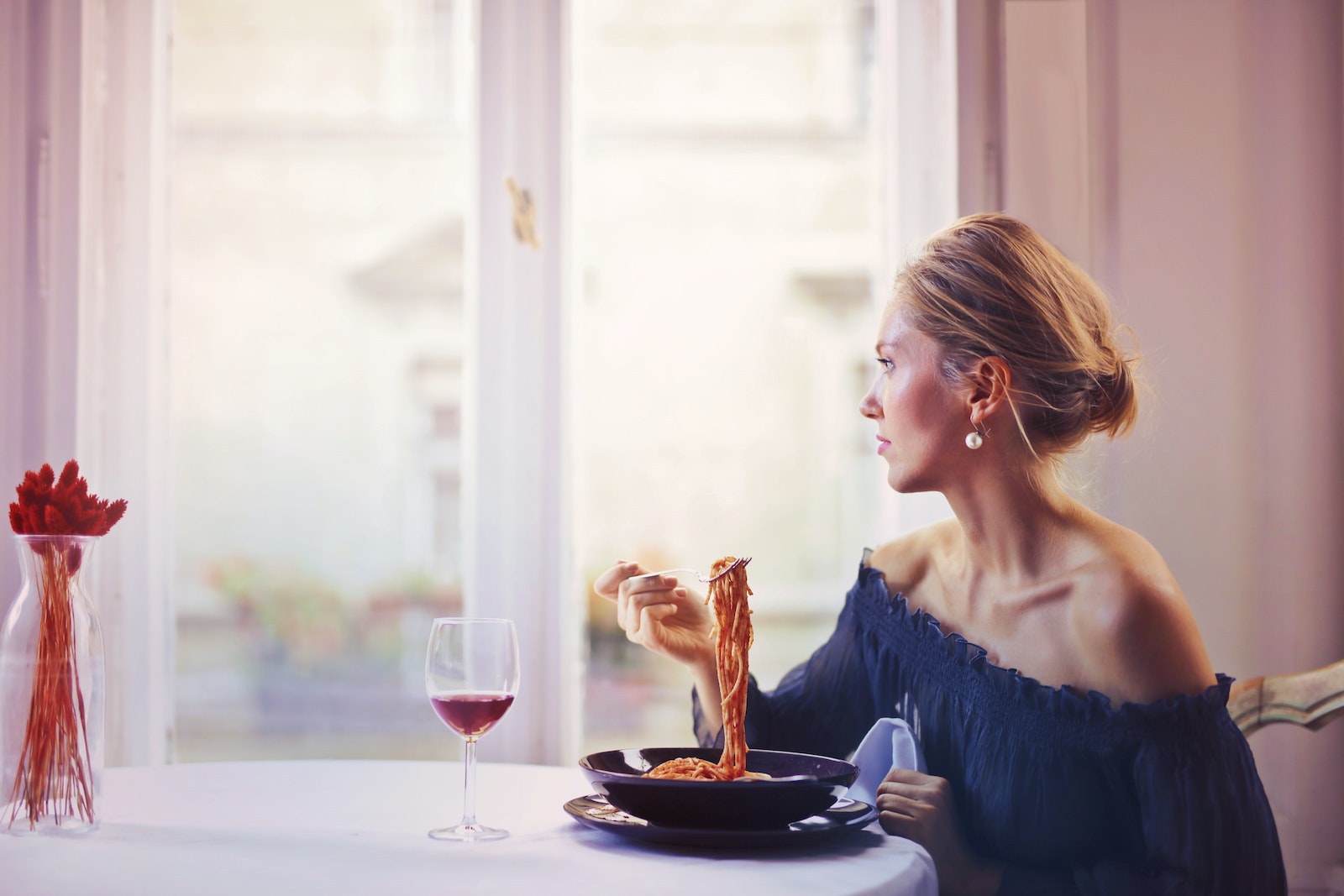 Woman Sitting on Chair While Eating Pasta Dish